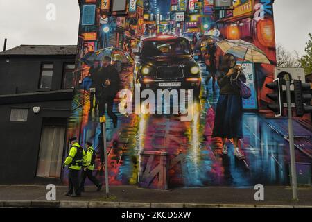 Deux policiers marchent devant une fresque colorée ‘Night taxi’ de l'artiste graffiti Dan Kitchener vu sur Enfield Street à Belfast. Mardi, 20 avril 2021, à Belfast, Irlande du Nord (photo d'Artur Widak/NurPhoto) Banque D'Images