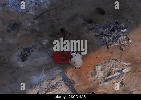 Un parent d'une victime qui est mort de la maladie de cornavirus (COVID-19) , recueille des cendres après crémation , dans un terrain de crématorium de masse , sur les rives du fleuve Ganga , à Allahabad sur 27 avril,2021. (Photo de Ritesh Shukla/NurPhoto) Banque D'Images