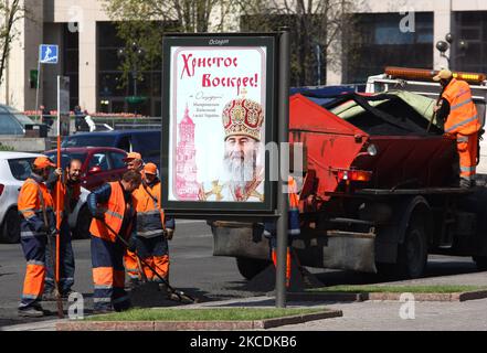 Les travailleurs communautaires travaillent sur la route à côté d'une bannière avec l'accueil de Pâques du chef de l'église orthodoxe ukrainienne du Patriarcat Onufry de Moscou sur la place de l'indépendance à Kiev, Ukraine, le 29 avril 2021. De 1 mai, des restrictions strictes de quarantaine dans la capitale ukrainienne seraient assouplies à mesure que le nombre de nouveaux cas de COVID-19 chuterait lentement, les transports publics terrestres et le métro commenceraient à fonctionner comme d'habitude, conformément aux normes et règles anti-épidémies, comme l'ont indiqué les médias locaux. Au cours des 24 dernières heures, 387 personnes sont mortes de complications de la coronavirus COVID-19 et 43 778 personnes sont mortes Banque D'Images