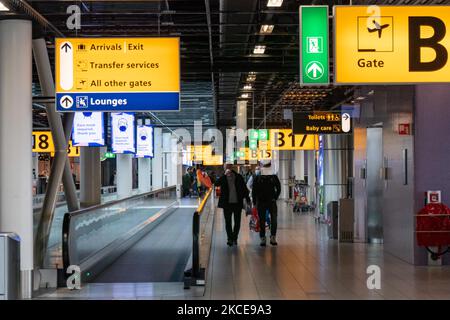 À l'intérieur du terminal de l'aéroport international d'Amsterdam-Schiphol pendant la pandémie de Covid-19. Le nombre réduit de passagers et l'équipage de conduite sont vus porter des équipements de protection comme les masques et les gants obligatoires, en gardant la distance entre eux pour éviter la propagation du coronavirus. Le nombre de passagers de l'aviation mondiale a diminué en raison des restrictions de voyage, des mesures de sécurité telles que les lockdowns, la quarantaine, la PCR et le test rapide avant les vols, pendant l'ère de la pandémie du coronavirus Covid-19 qui a durement frappé l'industrie de l'aviation et du voyage. Amsterdam, pays-Bas sur 4 mai 2021 (Phot Banque D'Images