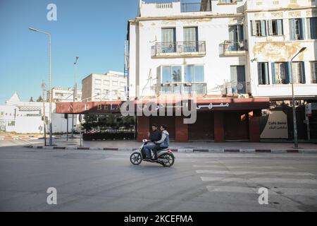 Deux jeunes hommes font le signe de la victoire (V) en faisant une moto dans une rue vide avec des magasins fermés dans la ville d'Ariana, région du Grand Tunis, Tunisie sur 13 mai 2021. Alors que les musulmans du monde entier célèbrent Eid ul-Fitr, et en raison du verrouillage partiel imposé par les autorités tunisiennes pour ralentir la propagation de la pandémie COVID-19, les fidèles n’ont pas exécuté la prière Eid ul-Fitr dans les mosquées fermées. Même les cafés étaient fermés, et il n'y avait aucune manifestation de festivités dans les rues. Les Tunisiens achètent simplement du pain, puis du Rentre à la maison. EID ul-Fitr également appelé TH Banque D'Images