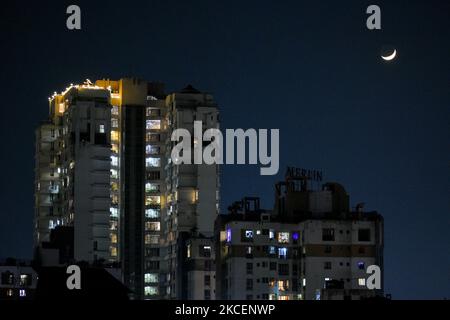 Un croissant de lune est vu au-dessus d'un complexe résidentiel de haute élévation entièrement éclairé , comme les gens se retirent à l'intérieur de leur maison pendant le premier jour de COVID-19 verrouillage à Kolkata, en Inde, le 16 mai 2021 . (Photo par Debarchan Chatterjee/NurPhoto) Banque D'Images