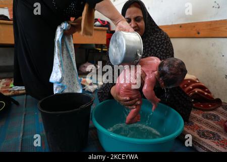 Une femme palestinienne assoit un bébé d'un jour dans un bool des Nations Unies où de nombreuses familles palestiniennes déplacées ont cherché refuge dans la ville de Gaza, dans le cadre de frappes aériennes et de bombardements des forces israéliennes sur 20 mai 2021. - Le bébé a été nommé d'après Mohammed Deif, le leader reclus de l'aile militaire du groupe islamiste palestinien Hamas. Israël et les Palestiniens sont embourbés dans leur pire conflit depuis des années alors qu'Israël livre la bande de Gaza avec des frappes aériennes et de l'artillerie, tandis que les militants du Hamas lancèrent des roquettes dans l'État juif. (Photo de Majdi Fathi/NurPhoto) Banque D'Images