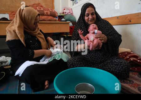 Une femme palestinienne assoit un bébé d'un jour dans un bool des Nations Unies où de nombreuses familles palestiniennes déplacées ont cherché refuge dans la ville de Gaza, dans le cadre de frappes aériennes et de bombardements des forces israéliennes sur 20 mai 2021. - Le bébé a été nommé d'après Mohammed Deif, le leader reclus de l'aile militaire du groupe islamiste palestinien Hamas. Israël et les Palestiniens sont embourbés dans leur pire conflit depuis des années alors qu'Israël livre la bande de Gaza avec des frappes aériennes et de l'artillerie, tandis que les militants du Hamas lancèrent des roquettes dans l'État juif. (Photo de Majdi Fathi/NurPhoto) Banque D'Images