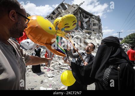 Un palestinien vend des ballons devant le bâtiment Al-Shuruq détruit par une attaque aérienne israélienne sur 22 mai 2021, à la suite d'un cessez-le-feu entre Israël et les militants palestiniens dans l'enclave à blocus israélien. - Comme le cessez-le-feu est en vigueur, l'aide humanitaire a commencé à entrer dans l'enclave ravagée par 11 jours de bain de sang. Alors que des milliers de Palestiniens déplacés sont retournés chez eux et que les Israéliens ont commencé à reprendre une vie normale un jour plus tôt, l'attention internationale s'est tournée vers la reconstruction de la bande de Gaza, qui a fait exploser la bombe. (Photo de Majdi Fathi/NurPhoto) Banque D'Images