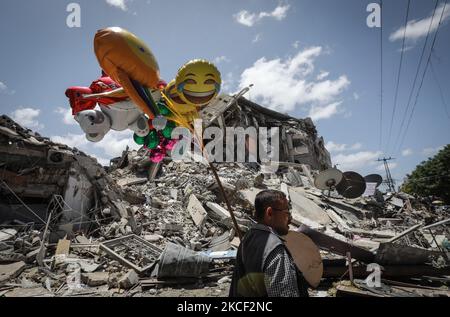 Un palestinien vend des ballons devant le bâtiment Al-Shuruq détruit par une attaque aérienne israélienne sur 22 mai 2021, à la suite d'un cessez-le-feu entre Israël et les militants palestiniens dans l'enclave à blocus israélien. - Comme le cessez-le-feu est en vigueur, l'aide humanitaire a commencé à entrer dans l'enclave ravagée par 11 jours de bain de sang. Alors que des milliers de Palestiniens déplacés sont retournés chez eux et que les Israéliens ont commencé à reprendre une vie normale un jour plus tôt, l'attention internationale s'est tournée vers la reconstruction de la bande de Gaza, qui a fait exploser la bombe. (Photo de Majdi Fathi/NurPhoto) Banque D'Images