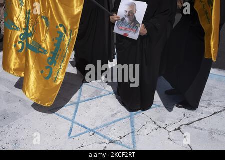 Une femme iranienne voilée détient un drapeau de la Zainebiyoun Divisiona et un portrait de l'ancien corps iranien des Gardiens de la révolution islamique (IRGC), le général Qasem Soleimani, Qui a été tué lors d'une attaque par drone américain à l'aéroport de Bagdad, tout en tenant un drapeau israélien lors d'un rassemblement en faveur du peuple palestinien, sur la place palestinienne dans le centre de Téhéran, sur 22 mai 2021. Un groupe d'hommes et de femmes iraniens se sont réunis sur la place palestinienne pour célébrer la victoire des Palestiniens sur Israël, selon la déclaration lue par un manifestant. (Photo de Morteza N Banque D'Images