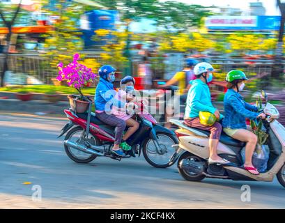 Personnes vietnamiennes conduite d'une moto avec le porte-fleur ou kumquat pot derrière la décoration de la maison pour le nouvel an lunaire à Ho Chi Minh, Vietnam Banque D'Images