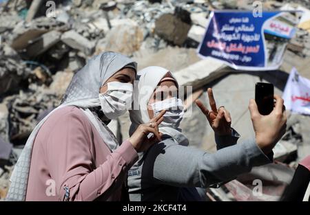 Les femmes palestiniennes posent pour une photo de "selfie" devant un bâtiment démoli dans le quartier commercial d'Al-Remal dans la ville de Gaza, récemment visé par des frappes aériennes israéliennes sur 23 mai 2021. - Les Gazaouis ont commencé à piecer leur vie après un conflit dévastateur avec Israël qui a tué plus de 200 personnes et fait des milliers de sans-abri dans l'enclave palestinienne appauvrie, des jours après qu'un cessez-le-feu négocié par l'Égypte ait mis fin à des frappes aériennes israéliennes mortelles et en a fait des tirs de roquettes vers Israël. (Photo de Majdi Fathi/NurPhoto) Banque D'Images