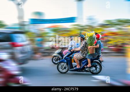 Personnes vietnamiennes conduite d'une moto avec le porte-fleur ou kumquat pot derrière la décoration de la maison pour le nouvel an lunaire à Ho Chi Minh, Vietnam Banque D'Images