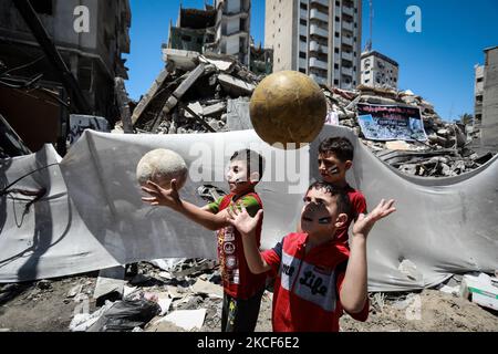 L'artiste palestinien Etaf al-Najili, 28 ans, peint le drapeau palestinien sur les visages des enfants près du site des frappes aériennes israéliennes dans la ville de Gaza, sur 24 mai 2021. (Photo de Majdi Fathi/NurPhoto) Banque D'Images