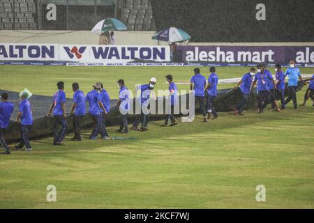 Le personnel au sol du stade couvre le terrain de cricket alors qu'il pleut lors du deuxième match international de cricket d'une journée (ODI) entre le Bangladesh et le Sri Lanka au stade national de cricket Sher-e-Bangla à Dhaka, sur 25 mai 2021. (Photo d'Ahmed Salahuddin/NurPhoto) Banque D'Images