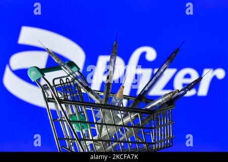 Les seringues médicales dans le mini chariot d'achat sont visibles devant le logo Pfizer affiché à l'écran. Le vendredi 28 mai 2021, à Dublin, Irlande. (Photo par Artur Widak/NurPhoto) Banque D'Images