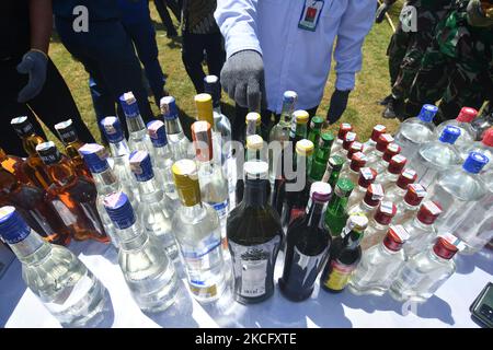 Les agents détruisent les boissons alcoolisées confisquées pour ne pas utiliser les timbres d'accise conformément aux règlements du Bureau de surveillance et de service des douanes (KPPBC) TMP C Pantoloan à Palu, province centrale de Sulawesi, Indonésie, le 10 juin 2021. Les agents des douanes et de l'accise ont arrêté, confisqué et détruit des milliers de bouteilles de boissons alcoolisées et de cigarettes illégales parce qu'elles ont nui aux finances du pays. (Photo par Mohamad Hamzah/NurPhoto) Banque D'Images