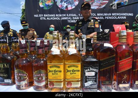 Les agents détruisent les boissons alcoolisées confisquées pour ne pas utiliser les timbres d'accise conformément aux règlements du Bureau de surveillance et de service des douanes (KPPBC) TMP C Pantoloan à Palu, province centrale de Sulawesi, Indonésie, le 10 juin 2021. Les agents des douanes et de l'accise ont arrêté, confisqué et détruit des milliers de bouteilles de boissons alcoolisées et de cigarettes illégales parce qu'elles ont nui aux finances du pays. (Photo par Mohamad Hamzah/NurPhoto) Banque D'Images