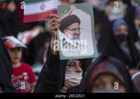 Une femme partisane du président iranien élu, Ebrahim Raisi, tient une affiche électorale de Raisi et le drapeau de l’Iran, tout en assistant à un rassemblement pour célébrer la victoire de Raisi aux élections présidentielles de 18 juin en Iran, dans le sud de Téhéran sur 19 juin 2021. Raisi a remporté les élections présidentielles iraniennes et a élu le nouveau président iranien. (Photo de Morteza Nikoubazl/NurPhoto) Banque D'Images