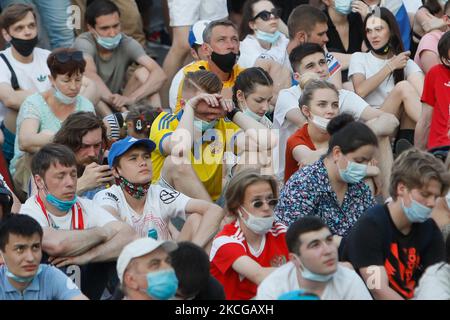 Le supporter ukrainien (C) regarde un flux en direct avec les supporters russes lors du match de l'UEFA Euro 2020 entre l'Australie et l'Ukraine sur 21 juin 2021 à la zone des fans sur la place Konyushennaya à Saint-Pétersbourg, en Russie. (Photo de Mike Kireev/NurPhoto) Banque D'Images