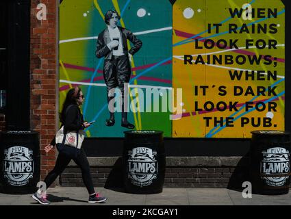 Une jeune femme marche à côté d'un pub avec une image d'Oscar Wilde et les mots "quand il Rain recherche Rainbows ; quand il est Dark look pour le Pub" dans le centre de Dublin. Le lundi 21 juin 2021, à Dublin, Irlande. (Photo par Artur Widak/NurPhoto) Banque D'Images