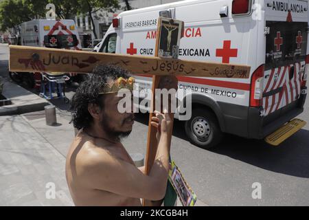 Une personne habillée comme Jésus-Christ tient une croix devant les ambulances pendant le premier simulacrum national 2021 sur l'Avenida Juárez, Mexico. Au cours du simulacre, des services d'urgence comme les pompiers, la police, la Croix-Rouge et le personnel du Secrétariat de la gestion intégrale des risques et de la protection civile de la capitale ont été déployés en cas de séisme de 8,1 Richter avec un épicentre à Guerrero, avec une perception très forte. (Photo de Gerardo Vieyra/NurPhoto) Banque D'Images