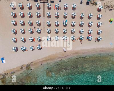 Tourisme en Grèce - Images aériennes panoramiques capturées à partir d'un drone de la plage de Stavros, située à Akrotiri près de la Canée. La plage est devenue très populaire en 70s car elle a présenté des scènes du film Zorba le grec avec Anthony Quinn. Les gens apprécient l'ombre du parasol et du transat d'un bar de plage, mais aussi d'autres ont posé leur serviette et se détendre pendant leurs vacances. La plage forme un petit port naturel à pied de la très raide montagne Vardies, où les rochers se submergent dans le cristal transparent turquoise exotique eau méditerranéenne de la plage. Les touristes aiment nager Banque D'Images