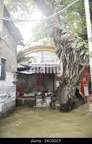 Un homme est assis devant un temple, alors que l'eau déborde du fleuve Ganga en raison de la marée haute à Kolkata, Inde, 26 juin, 2021. (Photo par Indranil Aditya/NurPhoto) Banque D'Images