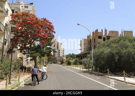 Les touristes passent à vélo dans une zone clôturée par l'armée turque depuis 1974 dans la zone côtière abandonnée de Varosha, une banlieue de la ville de Famagousta dans le nord de Chypre contrôlée par la Turquie. Samedi, 26 juin 2021. (Photo de Danil Shamkin/NurPhoto) Banque D'Images