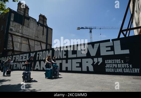 Les gens marchent à côté d'une murale géante 'Pass librement' par Asbestos, en collaboration avec la Hugh Lane Gallery, composée de près de 5 000 allumettes brûlées dessinées individuellement, chacune représentant la vie d'une personne qui est décédée de COVID-19 en Irlande. Le mercredi 30 juin 2021, à Dublin, Irlande. (Photo par Artur Widak/NurPhoto) Banque D'Images