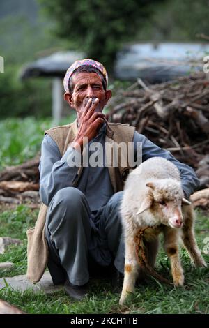 L'homme Gaddi fume un biddi (cigarette roulée à la main) alors qu'il tient un petit agneau dans le village de Mandher dans l'Himachal Pradesh, en Inde, sur 03 juillet 2010. (Photo de Creative Touch Imaging Ltd./NurPhoto) Banque D'Images