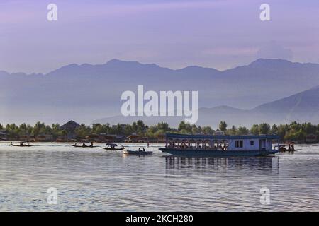 Le remorqueur tire un grand bateau qui sert de restaurant flottant tandis que les touristes dînent le long du lac Dal à Srinagar, Cachemire, Inde, sur 21 juillet 2010. (Photo de Creative Touch Imaging Ltd./NurPhoto) Banque D'Images