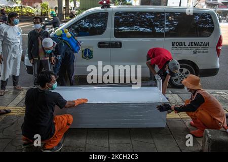 Les fonctionnaires enveloppent le cercueil contenant le corps d'un homme, 66 ans, de plastique après qu'il ait été trouvé mort sur un banc dans le centre-ville, soupçonné d'avoir le coronavirus COVID-19, à Jakarta sur 9 juillet 2021. L'Indonésie a imposé des restrictions d'urgence en raison de la nouvelle vague de COVID-19 à Java et sur l'île de Bali. Le pays a enregistré plus de 2 400 000 cas de coronavirus (COVID-19) et plus de 64 000 décès depuis le début de la pandémie. (Photo par Afriadi Hikmal/NurPhoto) Banque D'Images