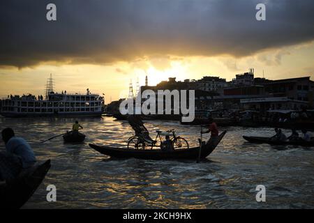 Un arrache-pousse tient son pousse-pousse alors qu'il traverse le fleuve Buriganga en bateau à l'aube à Dhaka, au Bangladesh, sur 15 juillet 2021. (Photo de Syed Mahamudur Rahman/NurPhoto) Banque D'Images