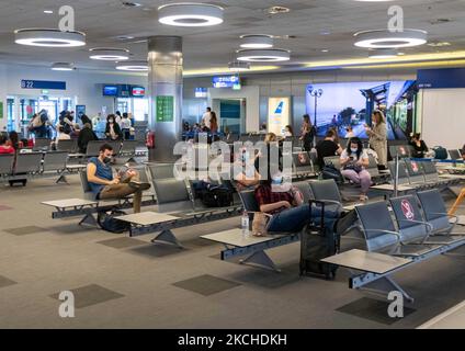 Personnes dans la salle d'attente devant les portes de l'aéroport d'Athènes. Passagers avec masques comme vu à l'aéroport international d'Athènes ATH LGAV Eleftherios Venizelos dans la capitale grecque. Les passagers arrivant utilisent l'aéroport pour se rendre aux îles et aux villes continentales éloignées avec des tests négatifs ou un passeport de vaccination vert. La Grèce est une destination de voyage populaire avec des plages célèbres et une industrie touristique fortement développée, avec une longue saison touristique car elle est située dans la partie sud de l'Europe dans les eaux méditerranéennes. La Grèce tente de stimuler son tourisme et de donner des privilèges à va Banque D'Images