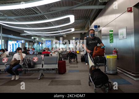 Personnes dans la salle d'attente devant les portes de l'aéroport d'Athènes. Passagers avec masques comme vu à l'aéroport international d'Athènes ATH LGAV Eleftherios Venizelos dans la capitale grecque. Les passagers arrivant utilisent l'aéroport pour se rendre aux îles et aux villes continentales éloignées avec des tests négatifs ou un passeport de vaccination vert. La Grèce est une destination de voyage populaire avec des plages célèbres et une industrie touristique fortement développée, avec une longue saison touristique car elle est située dans la partie sud de l'Europe dans les eaux méditerranéennes. La Grèce tente de stimuler son tourisme et de donner des privilèges à va Banque D'Images