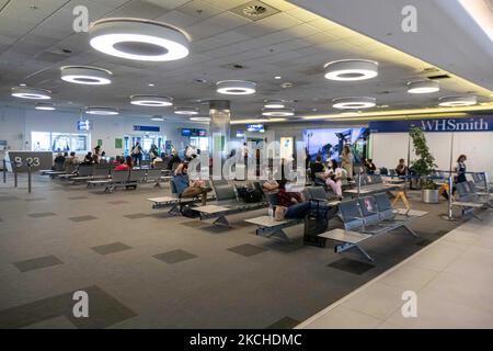 Personnes dans la salle d'attente devant les portes de l'aéroport d'Athènes. Passagers avec masques comme vu à l'aéroport international d'Athènes ATH LGAV Eleftherios Venizelos dans la capitale grecque. Les passagers arrivant utilisent l'aéroport pour se rendre aux îles et aux villes continentales éloignées avec des tests négatifs ou un passeport de vaccination vert. La Grèce est une destination de voyage populaire avec des plages célèbres et une industrie touristique fortement développée, avec une longue saison touristique car elle est située dans la partie sud de l'Europe dans les eaux méditerranéennes. La Grèce tente de stimuler son tourisme et de donner des privilèges à va Banque D'Images