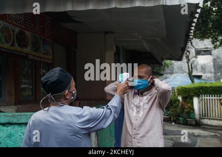 les musulmans indonésiens portant un masque de protection vérifient la température corporelle lorsqu'ils assistent à la prière d'Eid Al Adha lors des restrictions d'urgence de la COVID-19 le 20 juillet 2021 à Bandung, Indonésie. (Photo par Algi Febri Sugita/NurPhoto) Banque D'Images