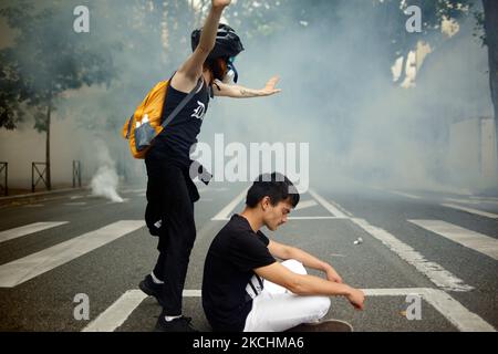 Un manifestant se tient dans des nuages de gaz lacrymogène devant les policiers anti-émeute comme un geste de fille. Plus de 10 000 manifestants sont descendus dans la rue à Toulouse contre la vaccination presque obligatoire et contre le pass sanitaire après le discours de Macron sur 12 juillet. Macron a annoncé que la carte santé sera obligatoire pour se rendre dans les lieux publics tels que les cafés, les théates, la salle de concerts, les cinémas, les magasins, Transports en commun (train, bus, tramway), etc. Le délai entre le premier jab et l'obtention du passe de santé sera de cinq semaines. Mais l'interdiction des espaces publics pour les personnes non vaccinées commencera sur au Banque D'Images