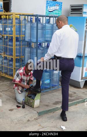 Un jeune garçon polit les chaussures d'un homme le long du bord de la route à la Romana, République dominicaine, sur 19 décembre 2012. (Photo de Creative Touch Imaging Ltd./NurPhoto) Banque D'Images