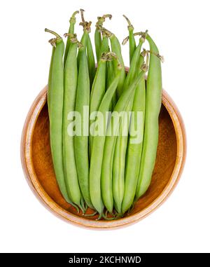 Haricots verts frais dans un bol en bois. Jeunes fruits non mûrs d'un cultivar du haricot commun ou aussi du haricot français, Phaseolus vulgaris. Banque D'Images