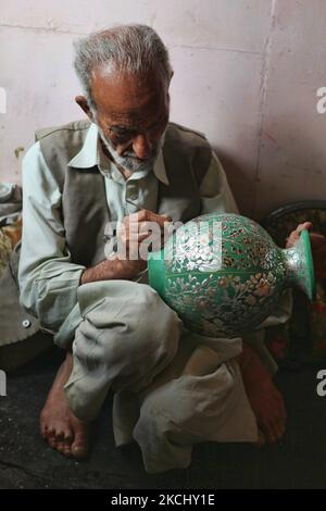 Un artisan cachemiri de 78 ans peint un dessin complexe sur un vase en forme de maché de papier dans un atelier flottant le long du lac Dal à Srinagar, Cachemire, Inde, sur 26 juin 2010. (Photo de Creative Touch Imaging Ltd./NurPhoto) Banque D'Images