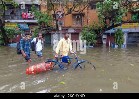 Un homme porte une bouteille de gaz GPL au milieu d'une rue inondée à Kolkata , en Inde , le 30 juillet 2021. Les prix des bouteilles de gaz GPL ont été élevés à plus de 140 roupies au cours du 6 dernier mois , en raison de la hausse des prix du pétrole brut . (Photo par Debarchan Chatterjee/NurPhoto) Banque D'Images