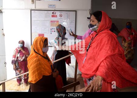 Le personnel de sécurité vérifie la température corporelle des travailleurs de l'habillement avant d'entrer dans une usine de vêtements après la réouverture des usines de vêtements pendant le confinement de Covid-19 à Dhaka, au Bangladesh, sur 1 août 2021. (Photo par Mamunur Rashid/NurPhoto) Banque D'Images