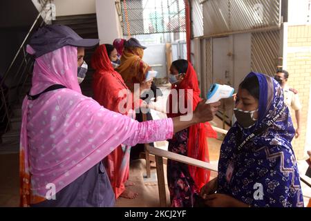 Le personnel de sécurité vérifie la température corporelle des travailleurs de l'habillement avant d'entrer dans une usine de vêtements après la réouverture des usines de vêtements pendant le confinement de Covid-19 à Dhaka, au Bangladesh, sur 1 août 2021. (Photo par Mamunur Rashid/NurPhoto) Banque D'Images