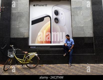 Un homme est assis sous un panneau d'affichage d'Apple iPhone 12 à Kolkata, Inde, 17 août 2021. (Photo par Indranil Aditya/NurPhoto) Banque D'Images