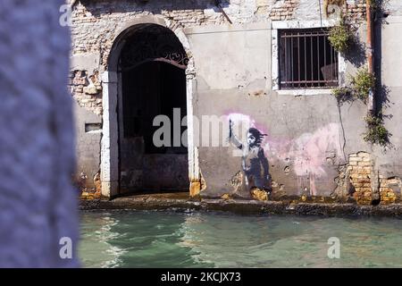 12/08/2021 Venezia, Italie. Une vue sur l'œuvre d'art Banksy présente un enfant migrant portant un gilet de sauvetage et portant une lumière rose fluo. Le graffiti a été peint sur une maison à Rio Novo qui de Piazzale Roma va au Grand Canal à côté de CA' Foscari. Après une année difficile pour le tourisme en raison de la pandémie Covid-19, les touristes, surtout italiens ou européens, reviennent à Venise pour raviver les zones les plus touristiques de la ville. (Photo de Mauro Ujetto/NurPhoto) Banque D'Images