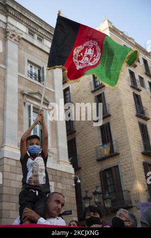 Un père élève son fils pour brandir le drapeau afghan lors d'un rassemblement pour sensibiliser la population à la situation en Afghanistan, à Barcelone, en Espagne, sur 18 août 2021. (Photo de Charlie Perez/NurPhoto) Banque D'Images