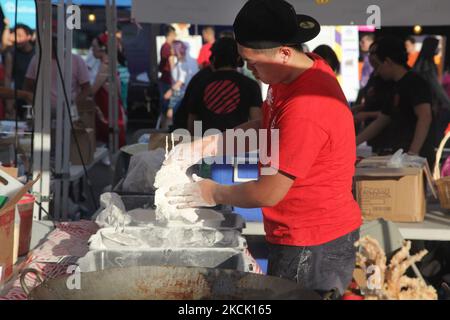 Le vendeur d'aliments couvre le calmar dans la pâte avant de la faire frire dans un grand wok rempli d'huile bouillante pendant un marché chinois nocturne à Markham, Ontario, Canada, on 24 juillet 2015. (Photo de Creative Touch Imaging Ltd./NurPhoto) Banque D'Images