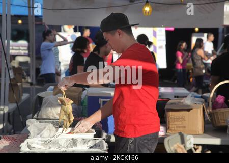 Le vendeur d'aliments couvre le calmar dans la pâte avant de la faire frire dans un grand wok rempli d'huile bouillante pendant un marché chinois nocturne à Markham, Ontario, Canada, on 24 juillet 2015. (Photo de Creative Touch Imaging Ltd./NurPhoto) Banque D'Images