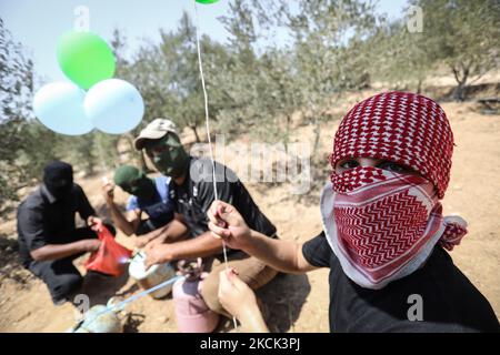 Les Palestiniens masqués préparent des ballons incendiaires près du camp de réfugiés de Bureij à Gaza, le long de la barrière frontalière entre Israël et Gaza, sur 24 août 2021. (Photo de Majdi Fathi/NurPhoto) Banque D'Images