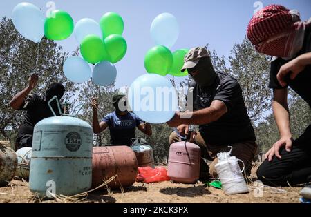 Les Palestiniens masqués préparent des ballons incendiaires près du camp de réfugiés de Bureij à Gaza, le long de la barrière frontalière entre Israël et Gaza, sur 24 août 2021. (Photo de Majdi Fathi/NurPhoto) Banque D'Images