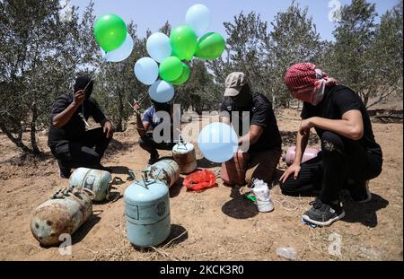 Les Palestiniens masqués préparent des ballons incendiaires près du camp de réfugiés de Bureij à Gaza, le long de la barrière frontalière entre Israël et Gaza, sur 24 août 2021. (Photo de Majdi Fathi/NurPhoto) Banque D'Images